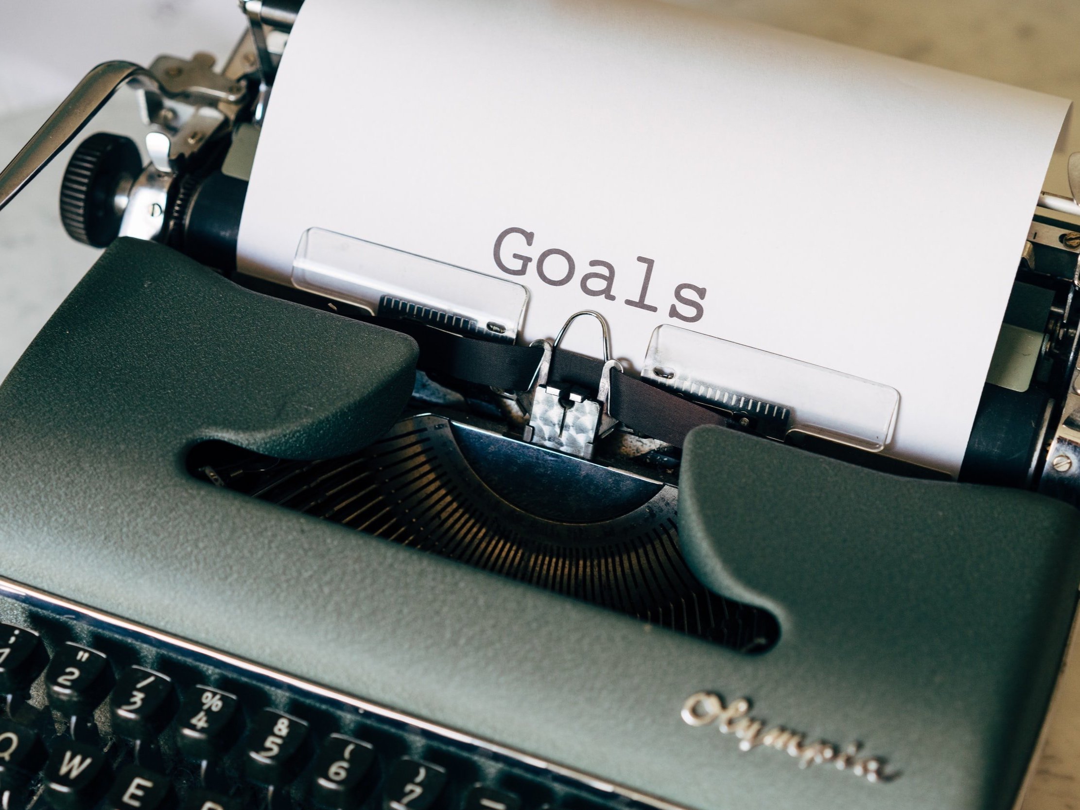 On a sheet of paper, a vintage typewriter with the word "Goals" typed out.