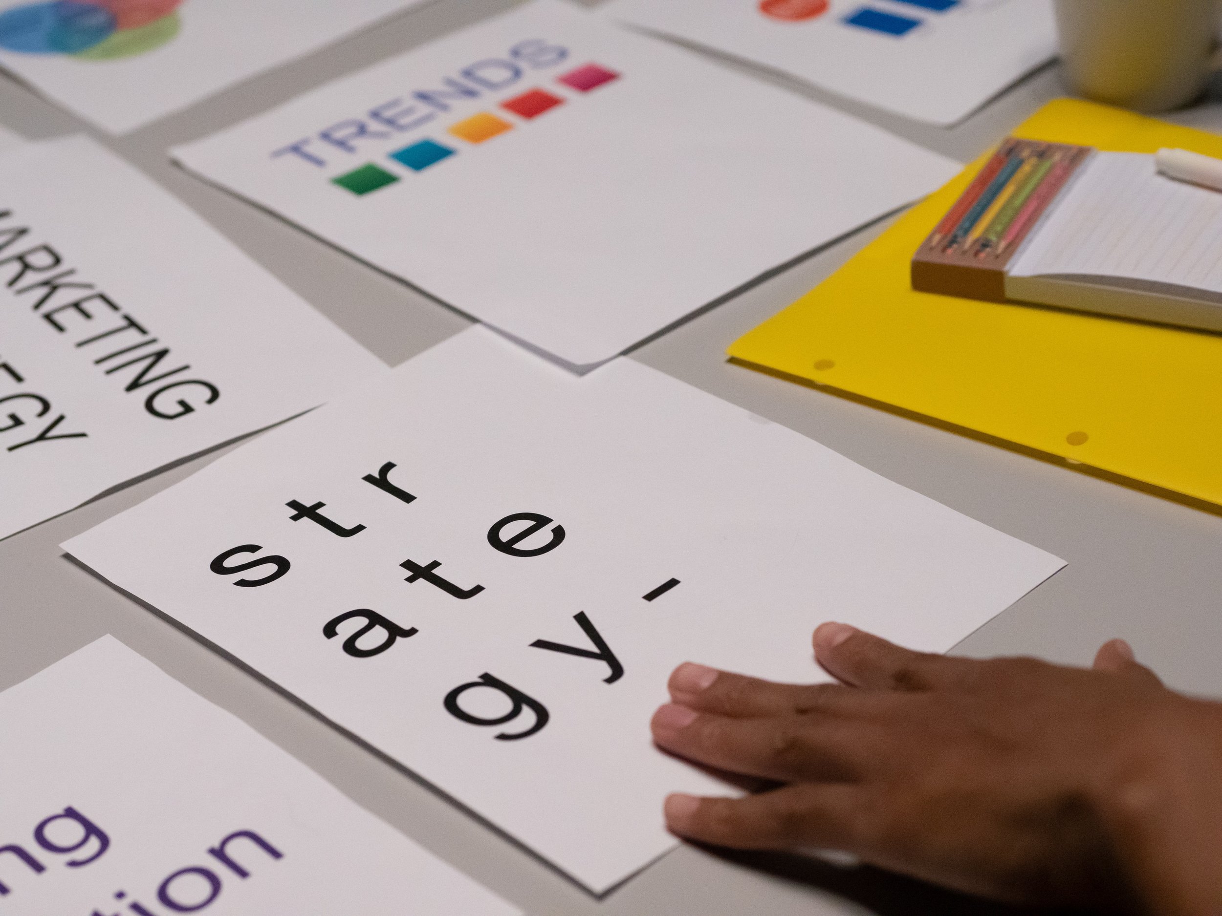 A hand on a piece of white paper with the word "strategy" written on it.