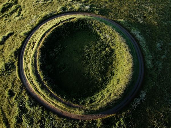 Aerial view of a circular path forming a closed loop in grass, symbolising comfort, repetition, and stalled creative progress.