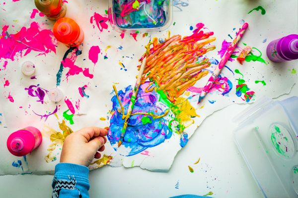 Child painting with bright colours on a messy workspace shows that creative thinking is for everyone, not just artists.