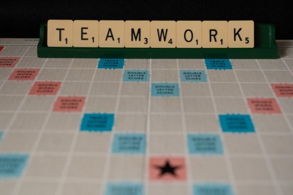 Scrabble tiles spelling "TEAMWORK" on a game board, emphasising the importance of collaborative effort.