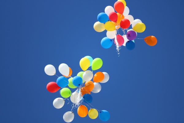 Colourful balloons soaring in a bright blue sky, represent freedom, joy, and looking ahead with optimism.