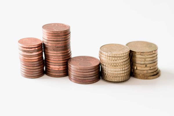 Stacks of pennies and other coins of various heights arranged in an abstract fashion on a plain white background.