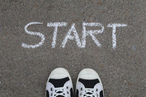 Sneakers on pavement with "START" written in chalk, illustrating that taking action now is key to achieving future success.