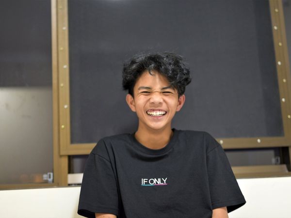 Young man in "If Only" shirt smiles, embodying perseverance towards design breakthroughs.
