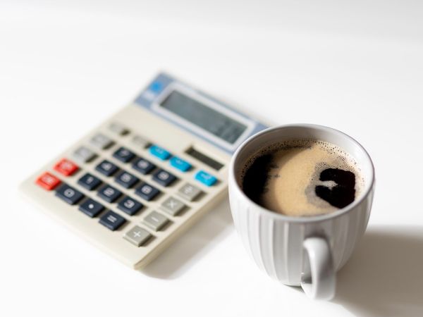 Calculator and coffee mug symbolize evaluating financial worth and rates, relating to not undervaluing oneself in business.