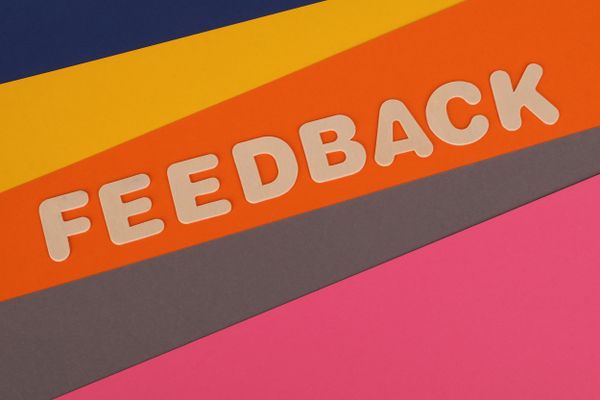 "Feedback" spelled in wooden letters on multi-colored paper backgrounds.