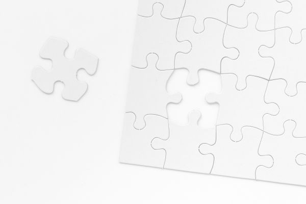 White jigsaw puzzle with several pieces missing, showing an incomplete or unfinished puzzle on white background.