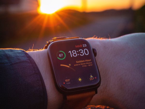 A person looking at his Apple Watch in front of the summer sun.