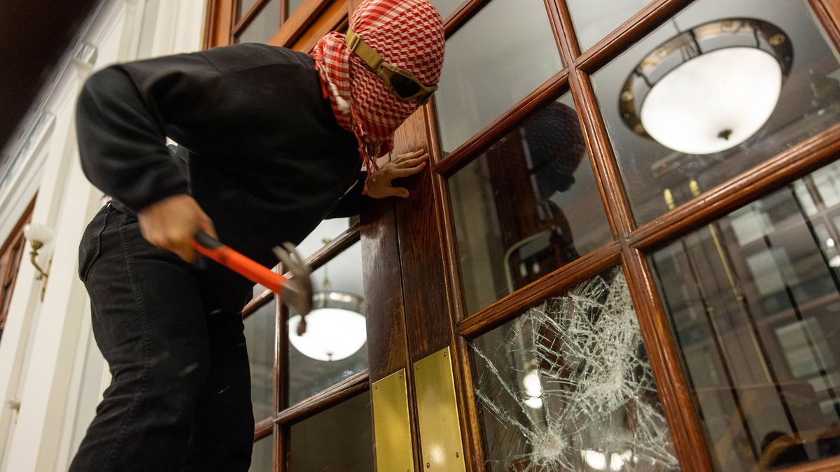 Üniversiteli bir protestocu Hamilton Hall'un ön kapısının etrafına zincir çekerek yetkililerin içeri girmesini engellemek üze