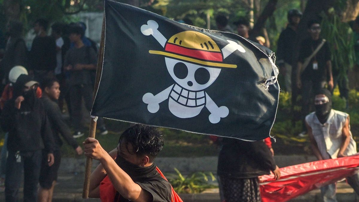 Bir protestocu, Surabaya'da düzenlenen protesto esnasında Endonezya ulusal bayrağını ve One Piece'den korsan bayrağını taşıyo