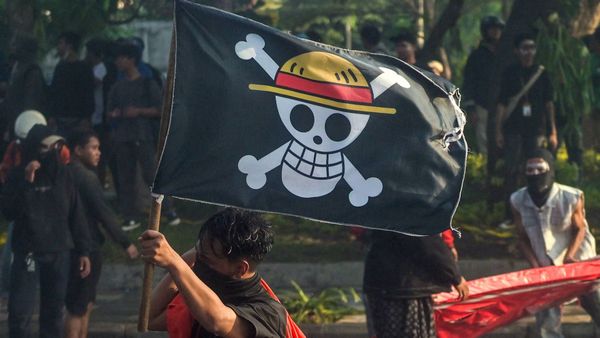 Bir protestocu, Surabaya'da düzenlenen protesto esnasında Endonezya ulusal bayrağını ve One Piece'den korsan bayrağını taşıyo