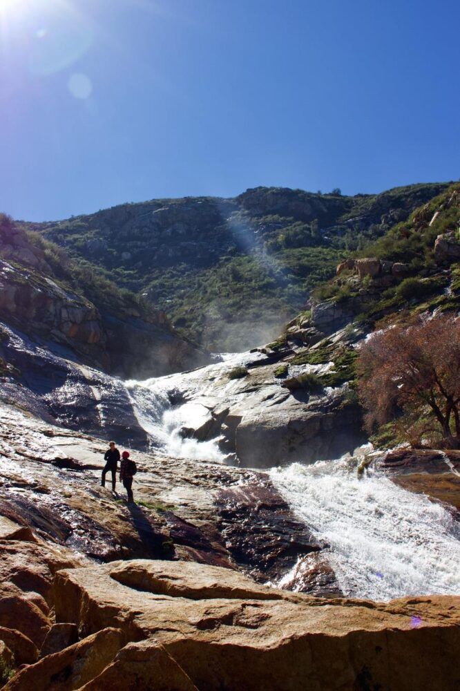 two people hiking by waterfall