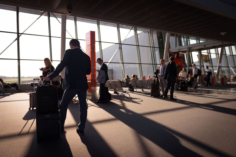 A young traveller with a suitcase walking through an airport departure hall