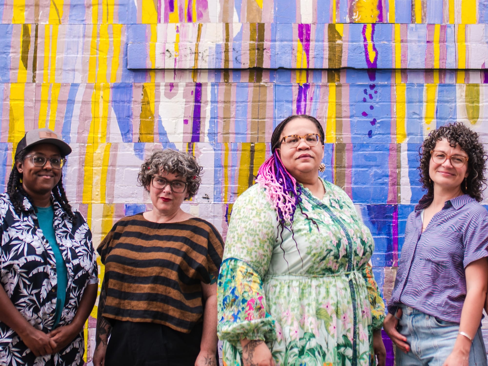 Group photo of the Scratch team standing in front of a colorful mural and looking somewhat intimidating.