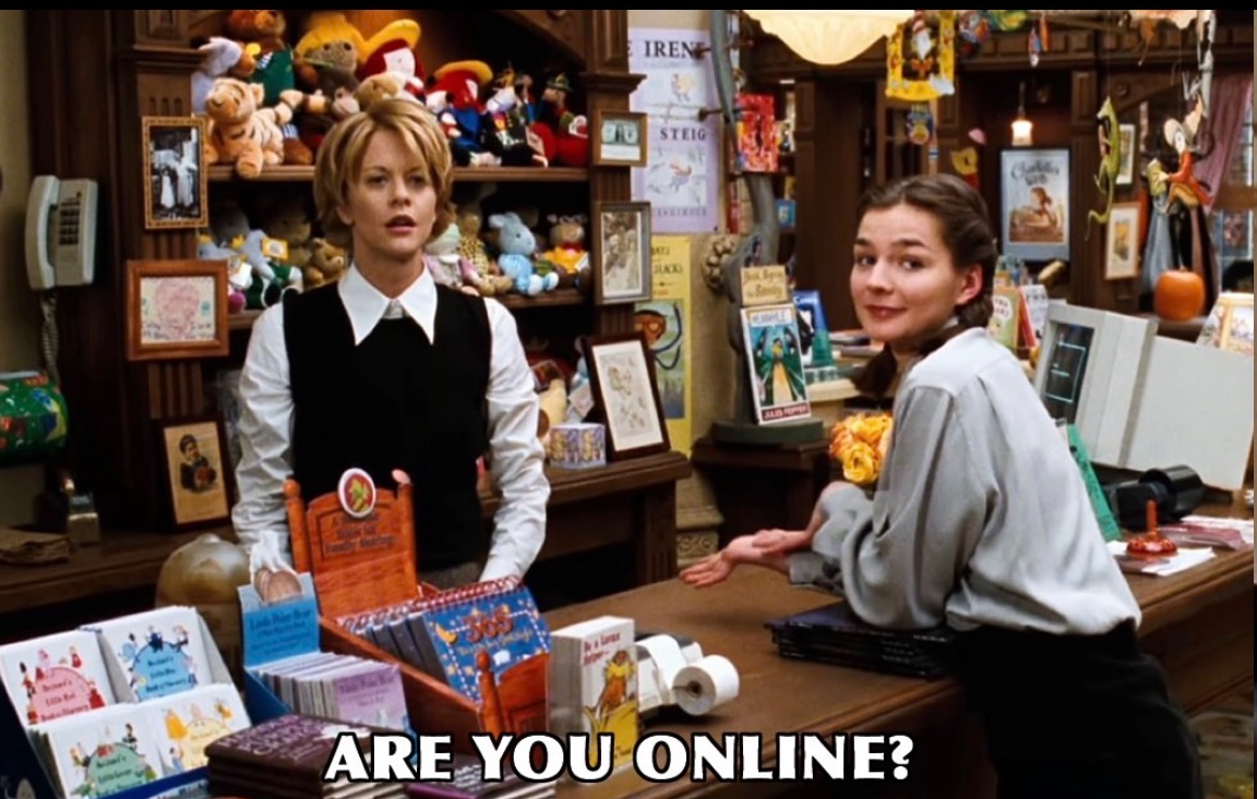 Still from the 1998 Nora Ephron film YOU'VE GOT MAIL, featuring two women standing at the counter of a children's bookstore. The caption reads ARE YOU ONLINE?