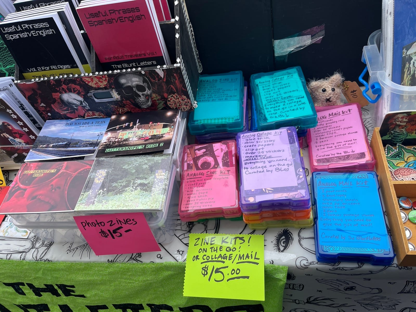 Zines, photo zines, and zine kits in many bright colors are for sale on a table.