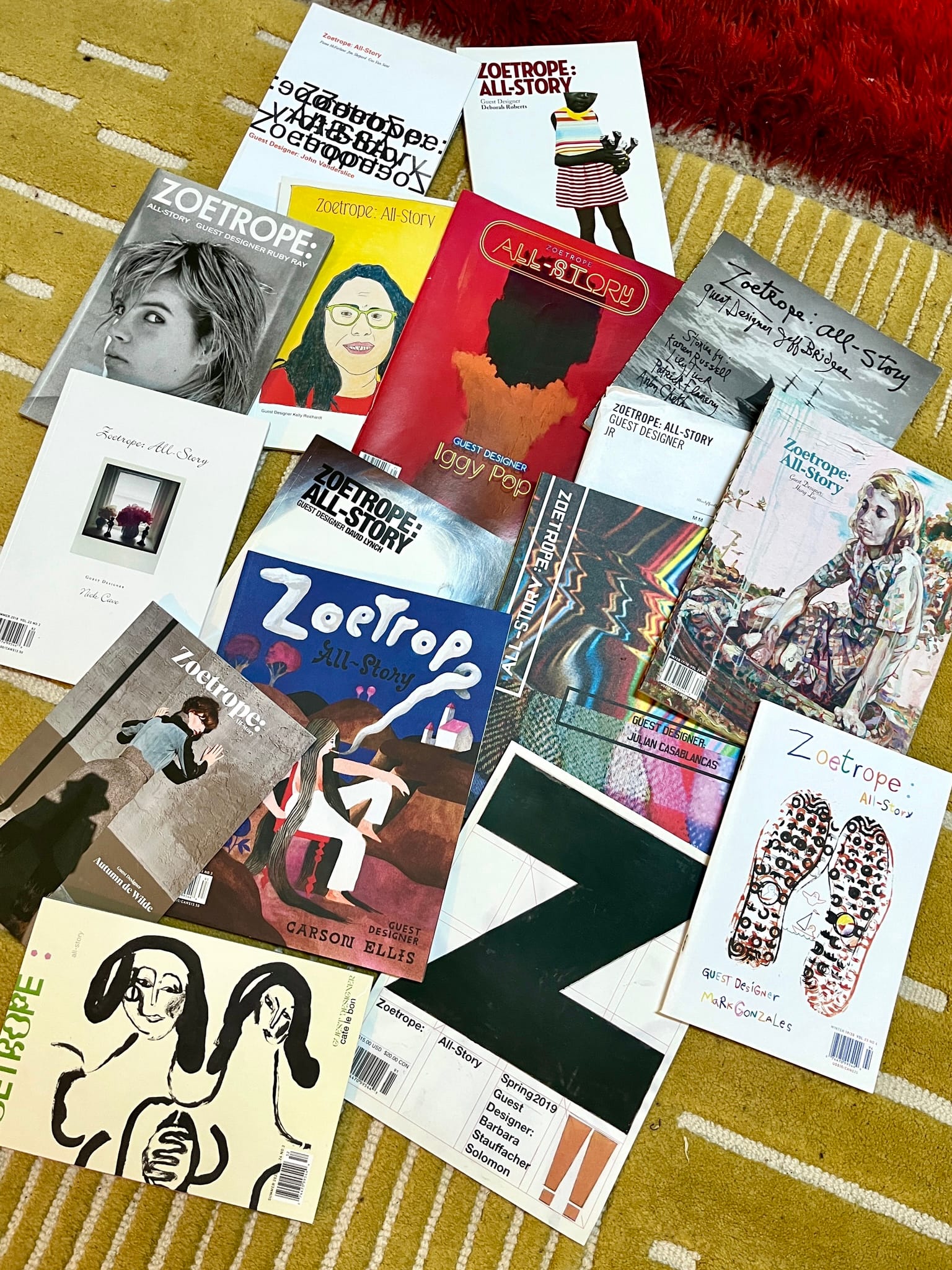 On a yellow and white rug, 16 issues of Zoetrope: All-Story, all different issues with different art covers are scattered.