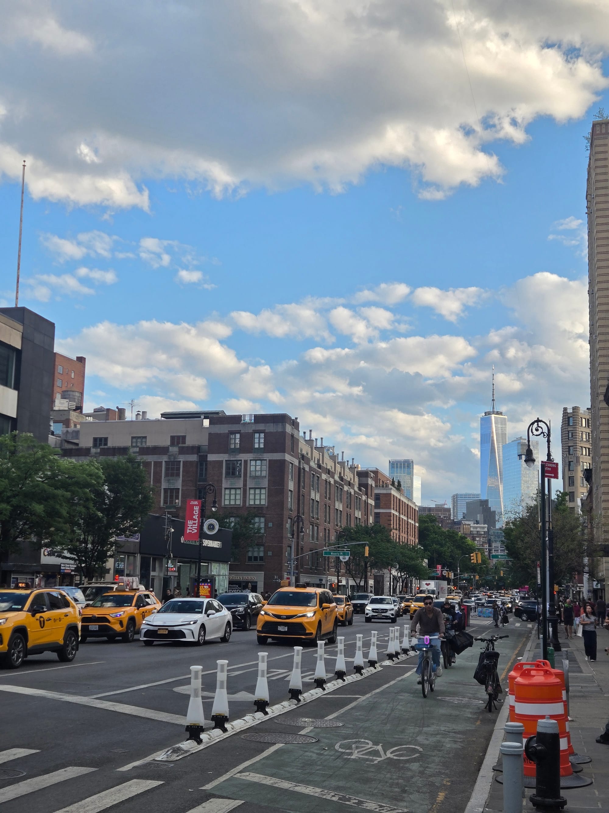 Image of taxis and cyclists traveling along an NYC street with a skyscraper in the background