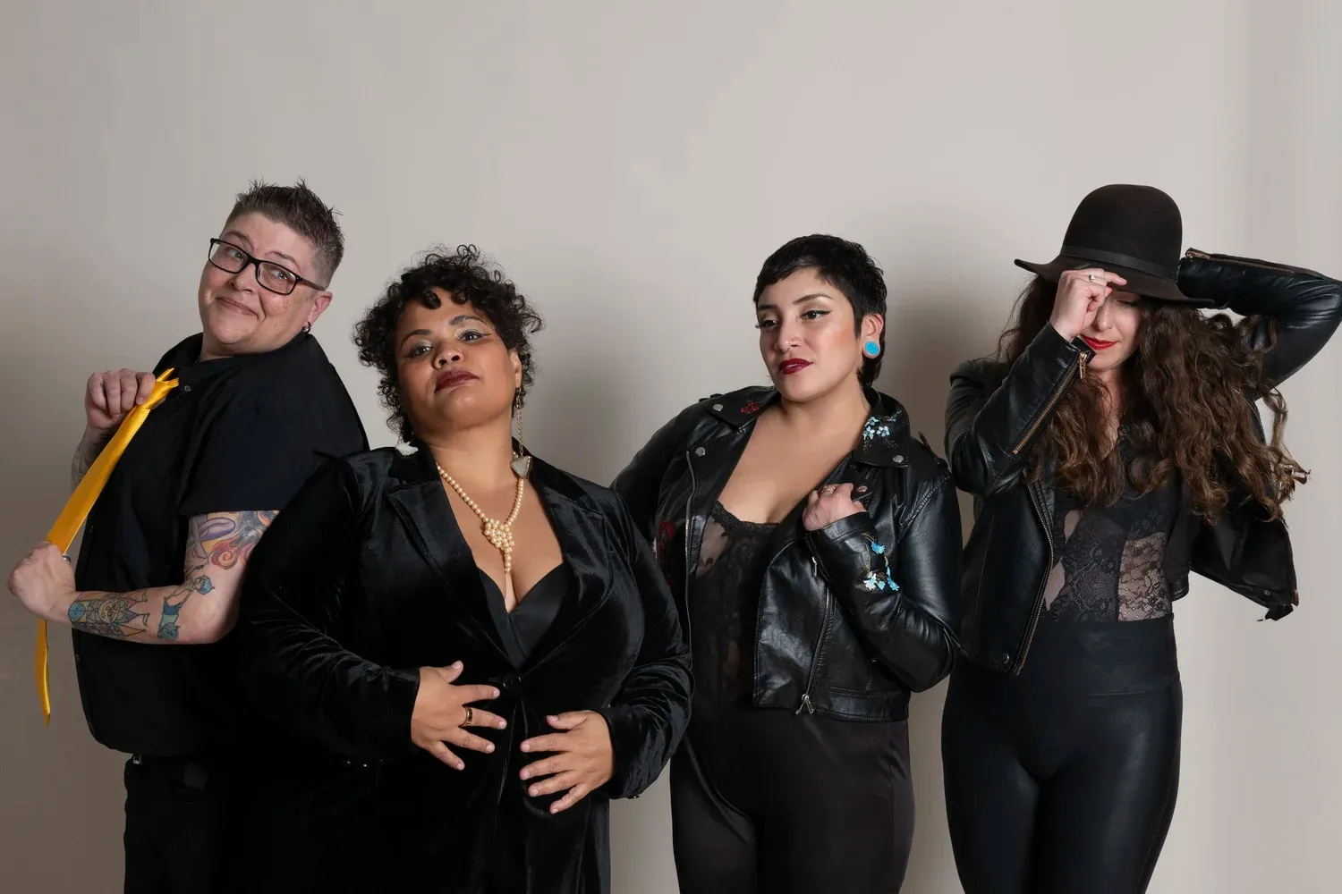 Four band members pose for a photo, all dressed in black. 