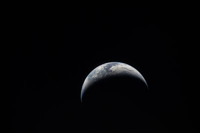 a photograph of earth from the Artemis mission, black background adn a crescent of earth: blue, green and white clouds are visible.