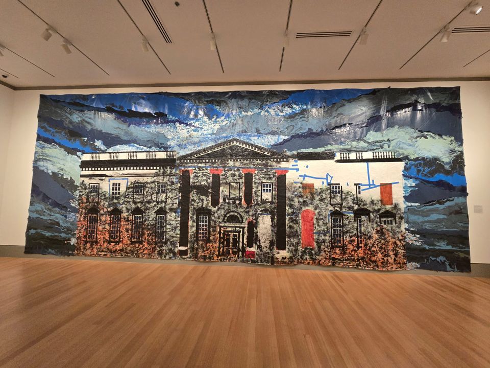 A large painting on paper, of the White House, with dark blue sky, and decaying, ripped front columns in a museum gallery. 