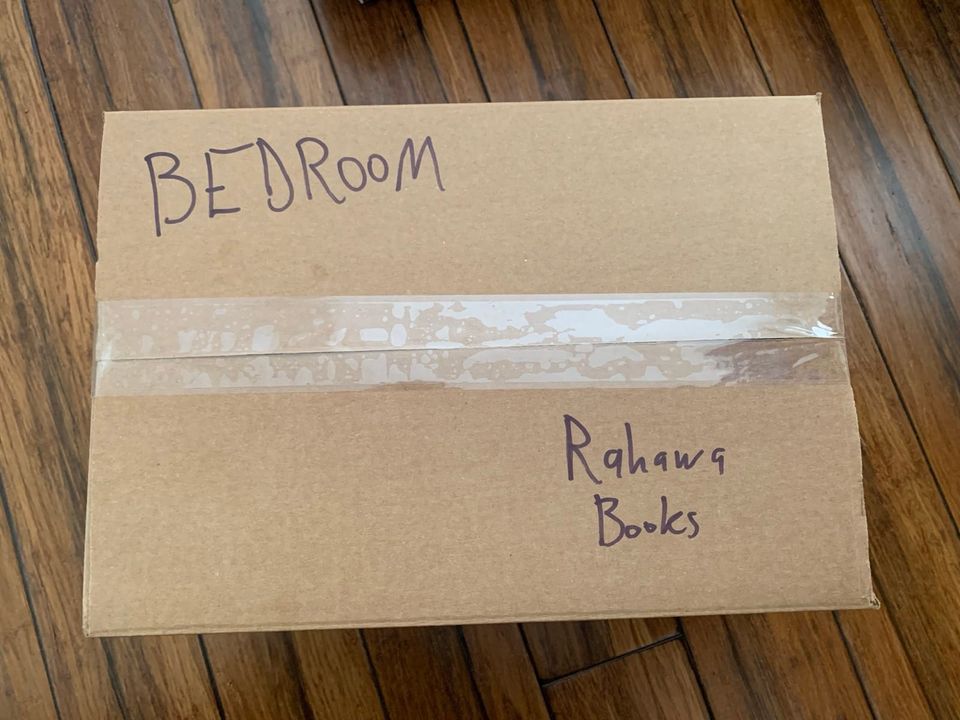 The top of a brown moving box that reads "Bedroom: Rahawa Books"