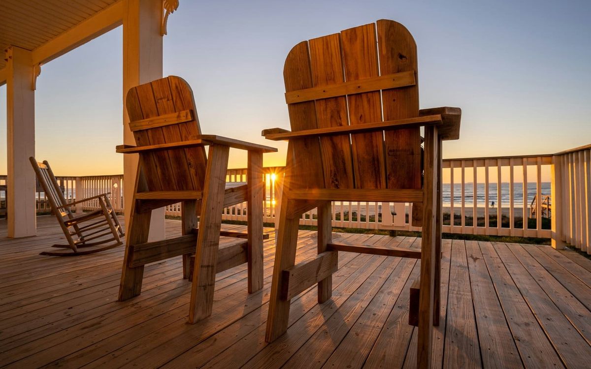 Two empty wooden chairs on a quiet porch in warm evening light.