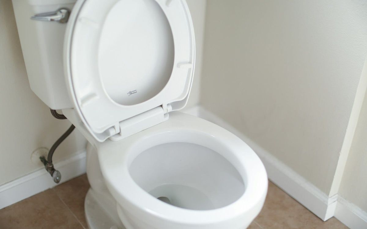 An ordinary white toilet with the lid raised in a small bathroom.