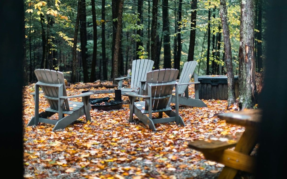 Empty wooden chairs gathered beneath trees at a quiet campsite.