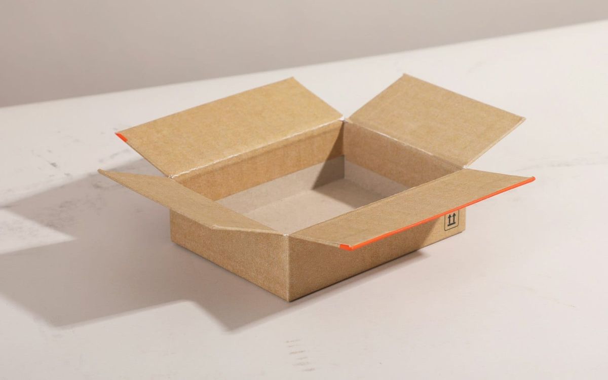 A plain open cardboard shipping box on a light tabletop.