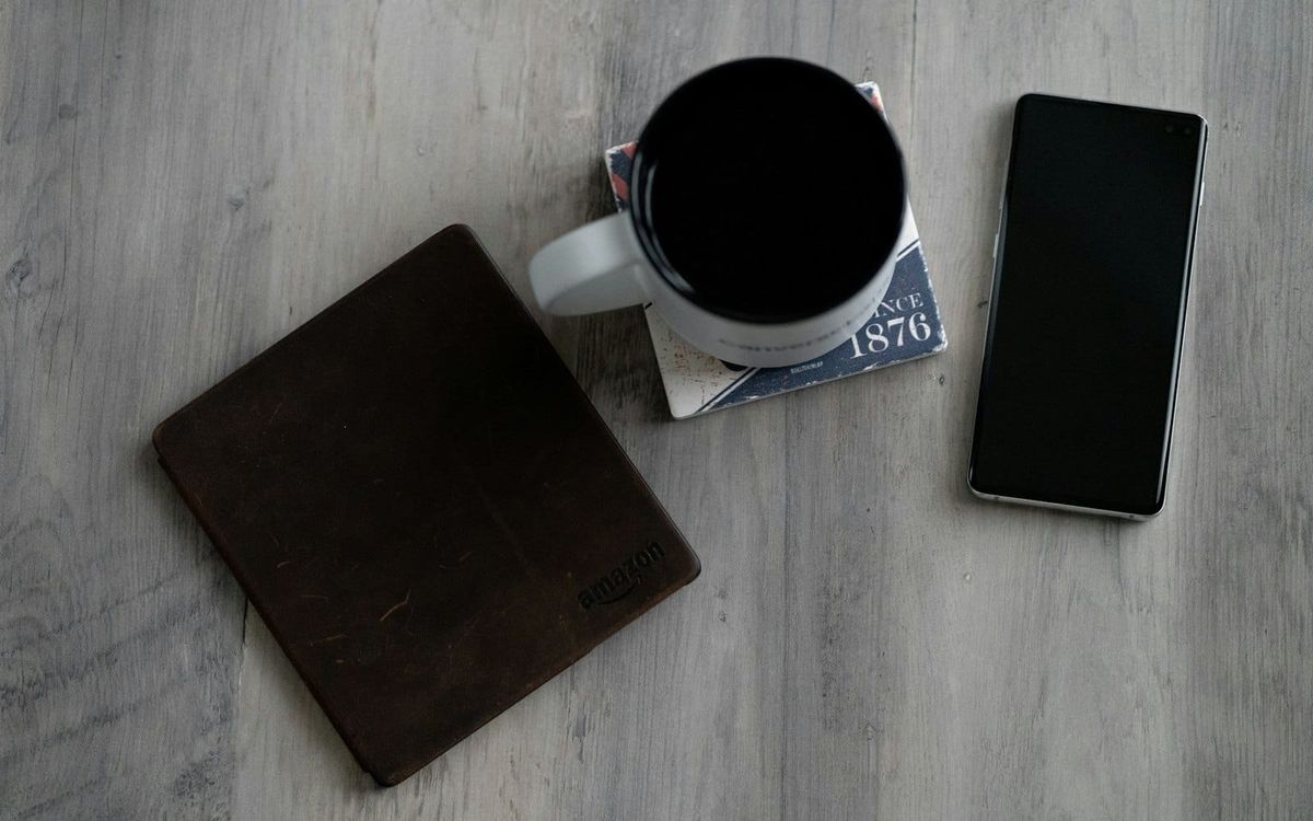 A dark smartphone beside a coffee mug and wallet on a table