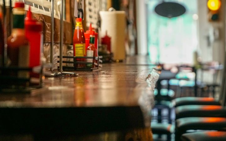 An everyday diner counter with empty stools and condiment bottles.