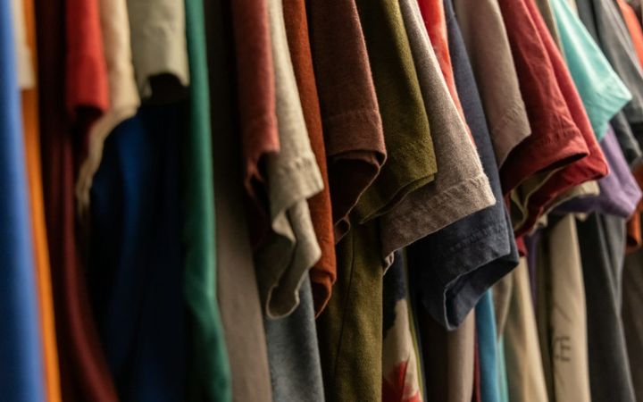 A row of everyday cotton shirts hanging on a clothing rack.
