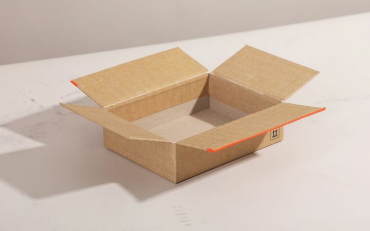 A plain open cardboard shipping box on a light tabletop.