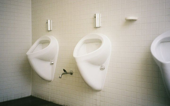 Two urinals in an empty tiled public restroom