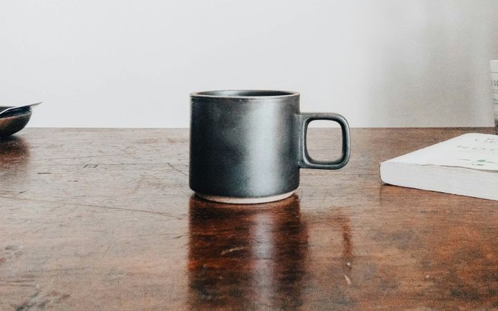 A plain dark ceramic coffee mug on a wooden table