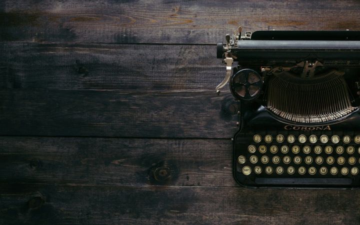 Part of an old manual typewriter on a weathered wooden desk