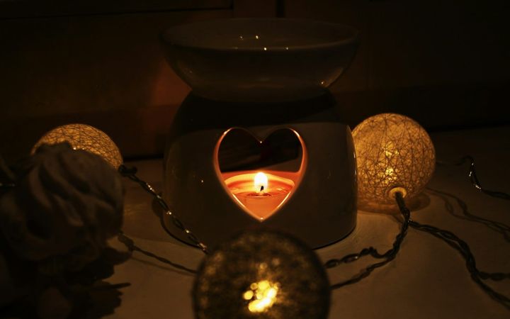 A tealight glowing inside a ceramic fragrance burner