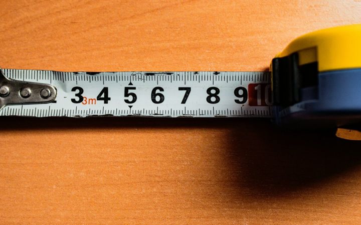 A tape measure extended across a wooden work surface