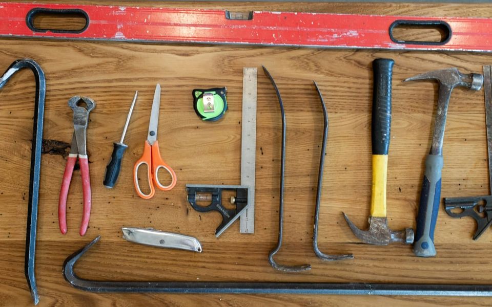 Basic hand tools and fasteners arranged on a worn wooden workbench.