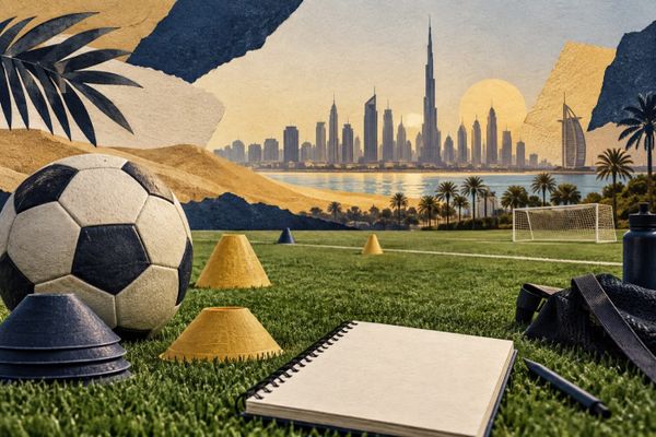 Fußball, Trainingshütchen und ein Notizbuch vor einer illustrierten Dubai-Skyline, redaktionelles Motiv zur neuen FC Bayern Akademie.