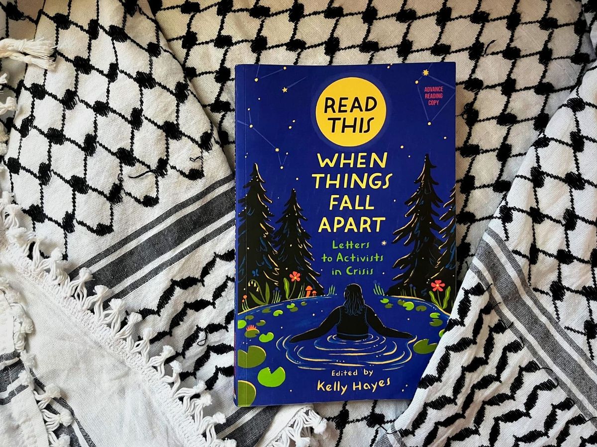A copy of the book "Read This When Things Fall Apart" Edited by Kelly Hayes is seen on top of a keffiyeh