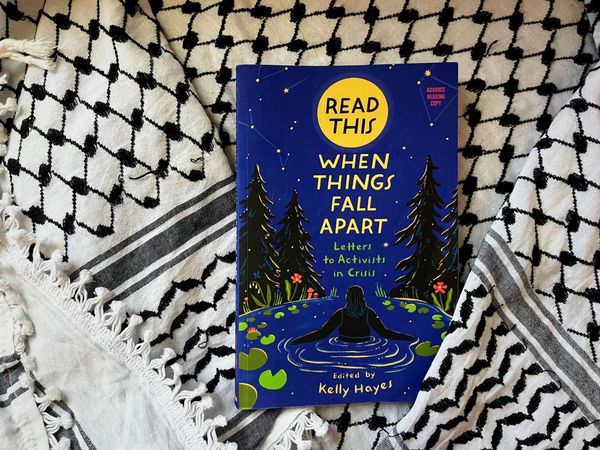 A copy of the book "Read This When Things Fall Apart" Edited by Kelly Hayes is seen on top of a keffiyeh