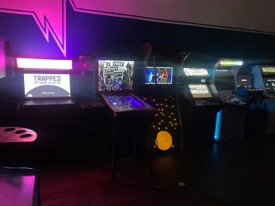 A row of custom arcade cabinets glowing in the dark at Wonderville in Brooklyn