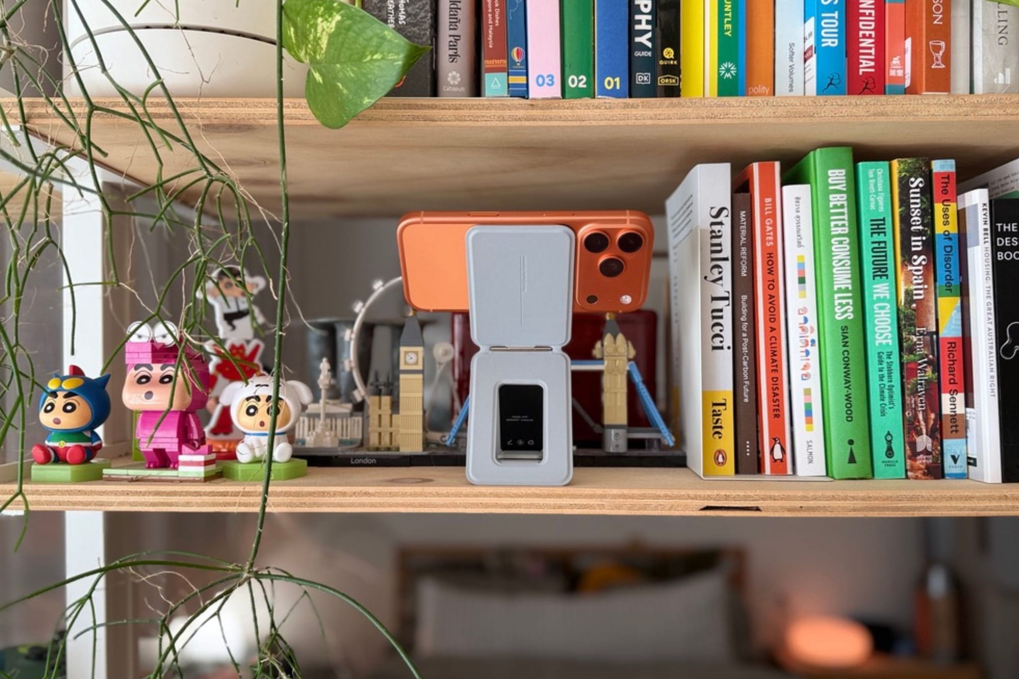 MOFT Snap Phone Tripod Stand attached to an iPhone and positioned on a bookshelf in landscape orientation for overhead filming