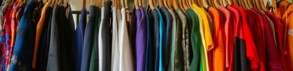 Clothes in many different colours hanging from a rail