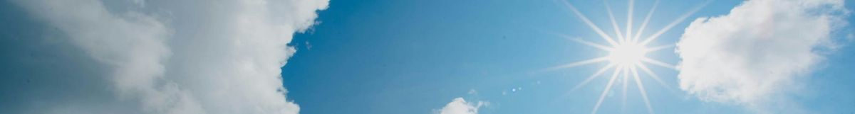 The sun in the sky, with a few white clouds.