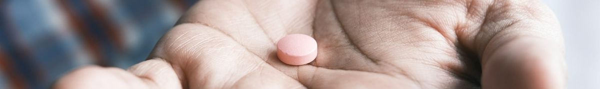 A pill resting on the palm of a hand.