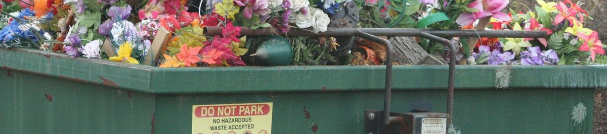 A large waste container full of colourful flowers.